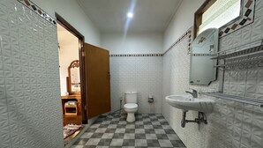 A bathroom with a checkered floor, white patterned walls, a toilet, a sink, and a mirror.