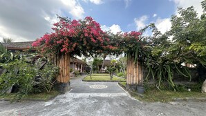 A gated entrance with a decorative archway, a paved pathway, and a well-maintained garden area.