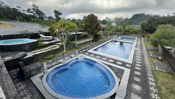 A pool area with multiple swimming pools, surrounded by stone steps and greenery.