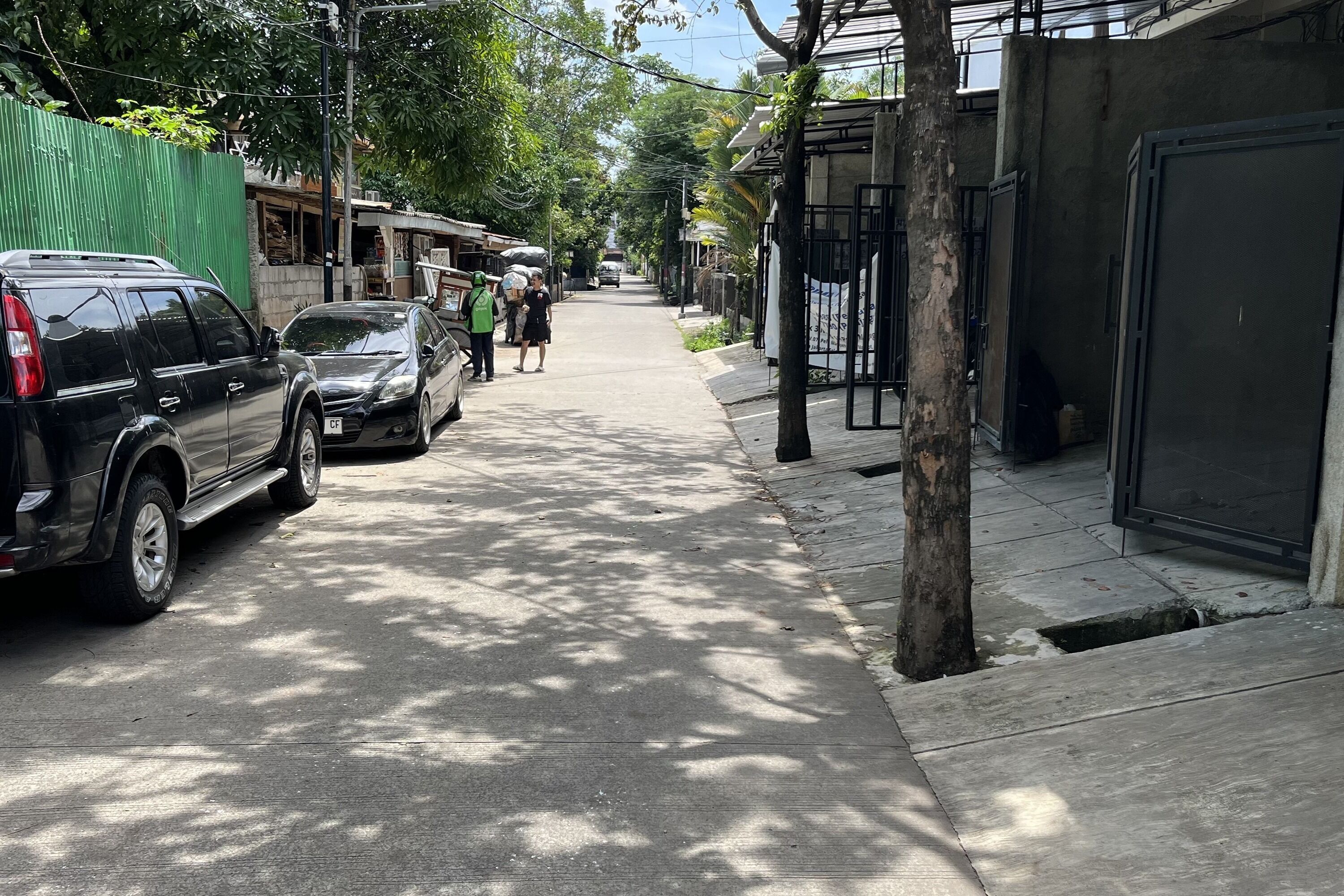 A narrow street lined with parked cars and buildings.