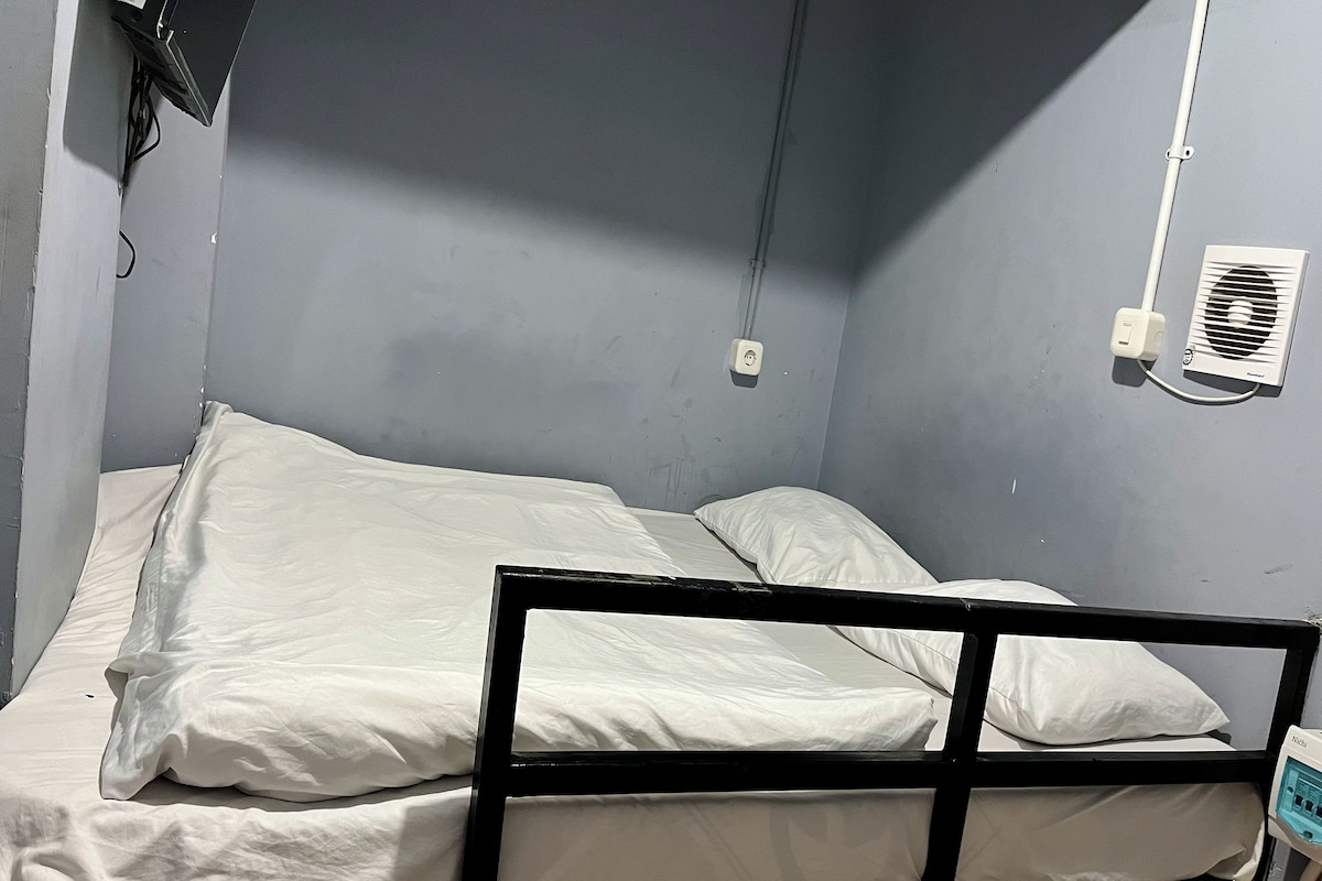 A single bed with white bedding in a room with grey walls.