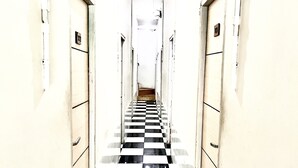 A narrow hallway with a black and white checkered floor, flanked by beige walls and doors. - Morroi Residence Kemang (Jakarta)