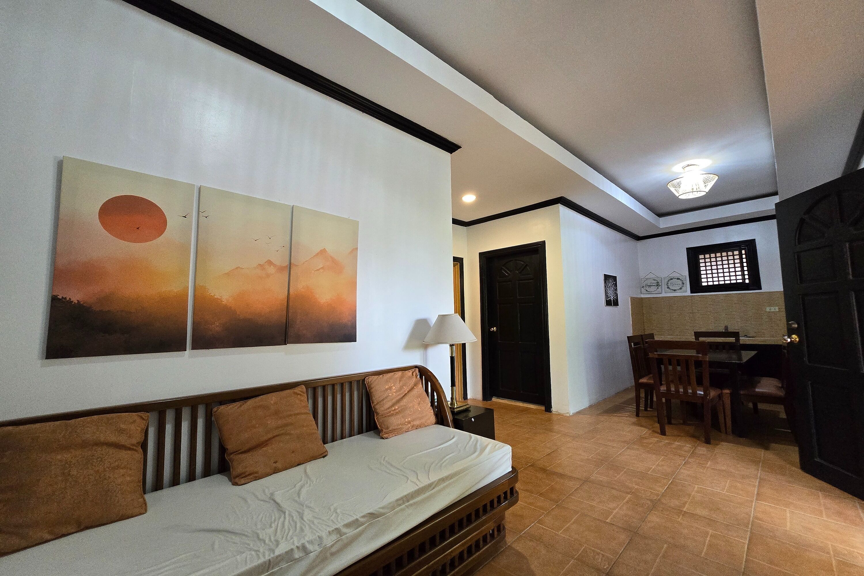A room with a bed, a dining table with chairs, a lamp, and artwork on the wall.