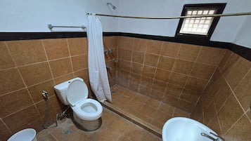 Un baño con inodoro, lavamanos, ducha y una ventana pequeña.