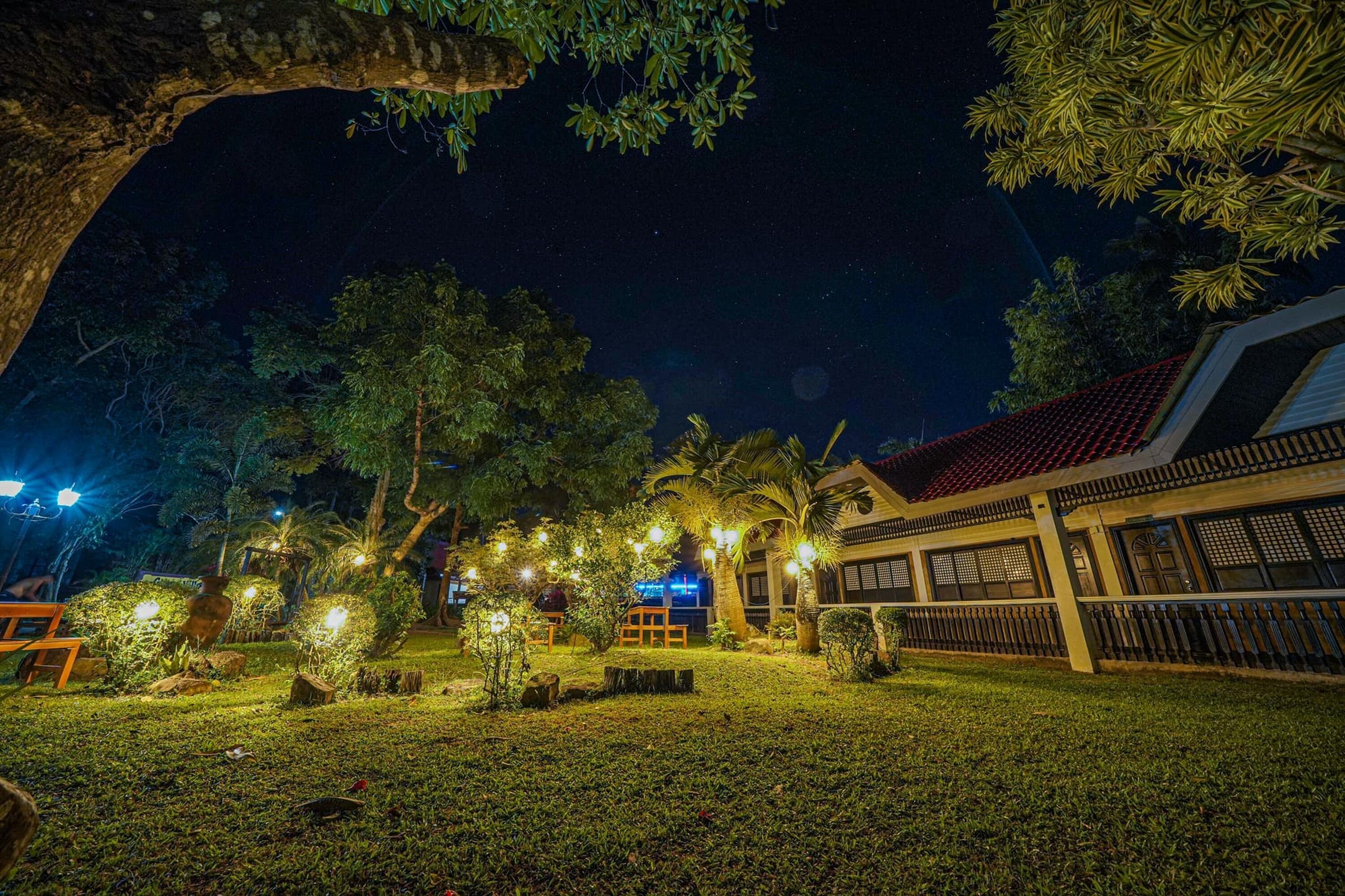 A well-lit outdoor area with a building, trees, and a bench.