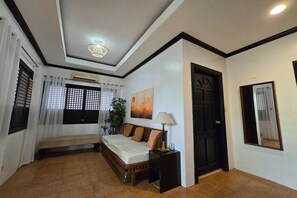 A bedroom with a bed, bedside table, lamp, and a painting on the wall. - Grand Villa Laguna (Bay)