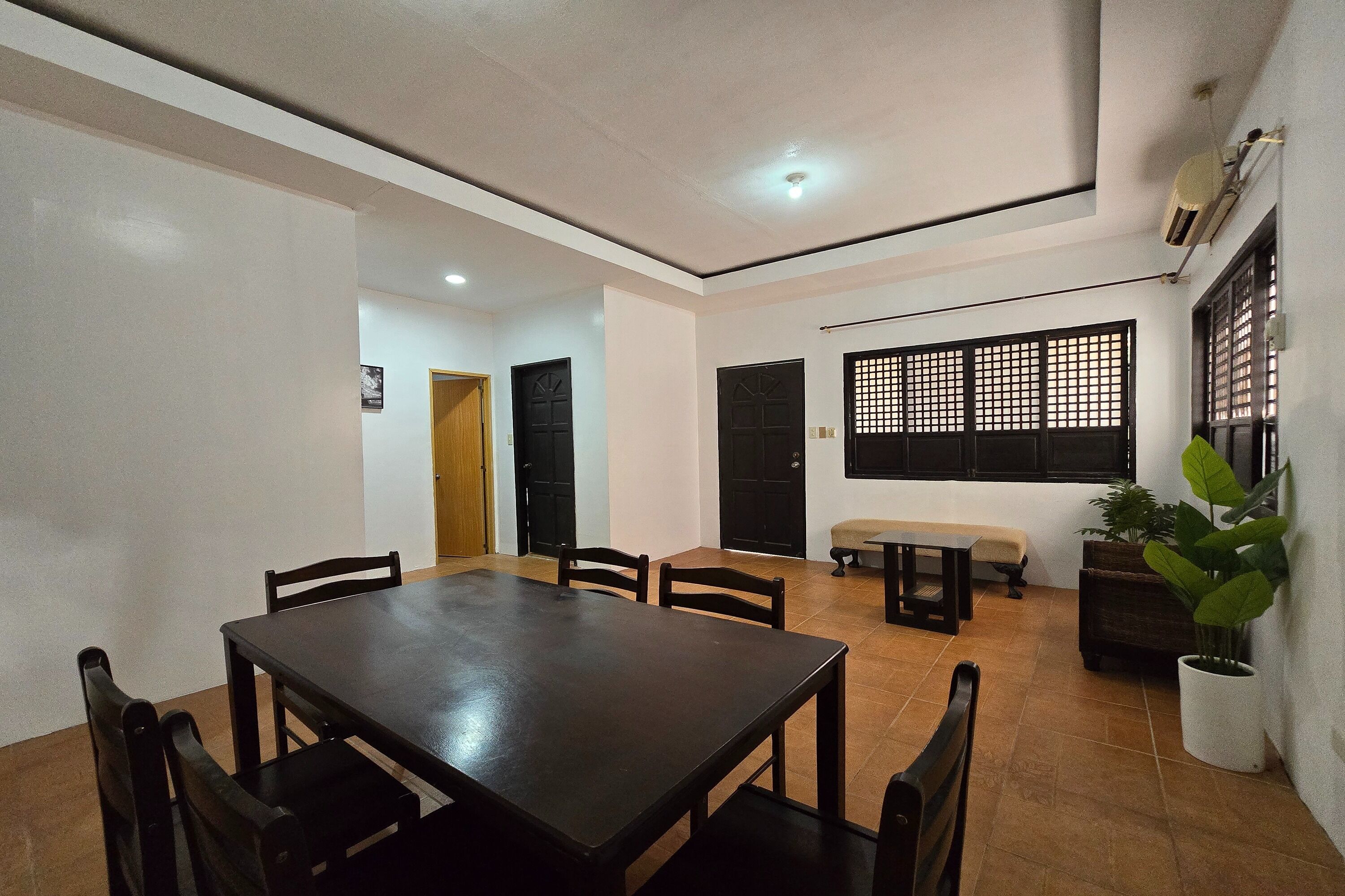 A dining area with a rectangular table and six chairs, a bench, and a potted plant.