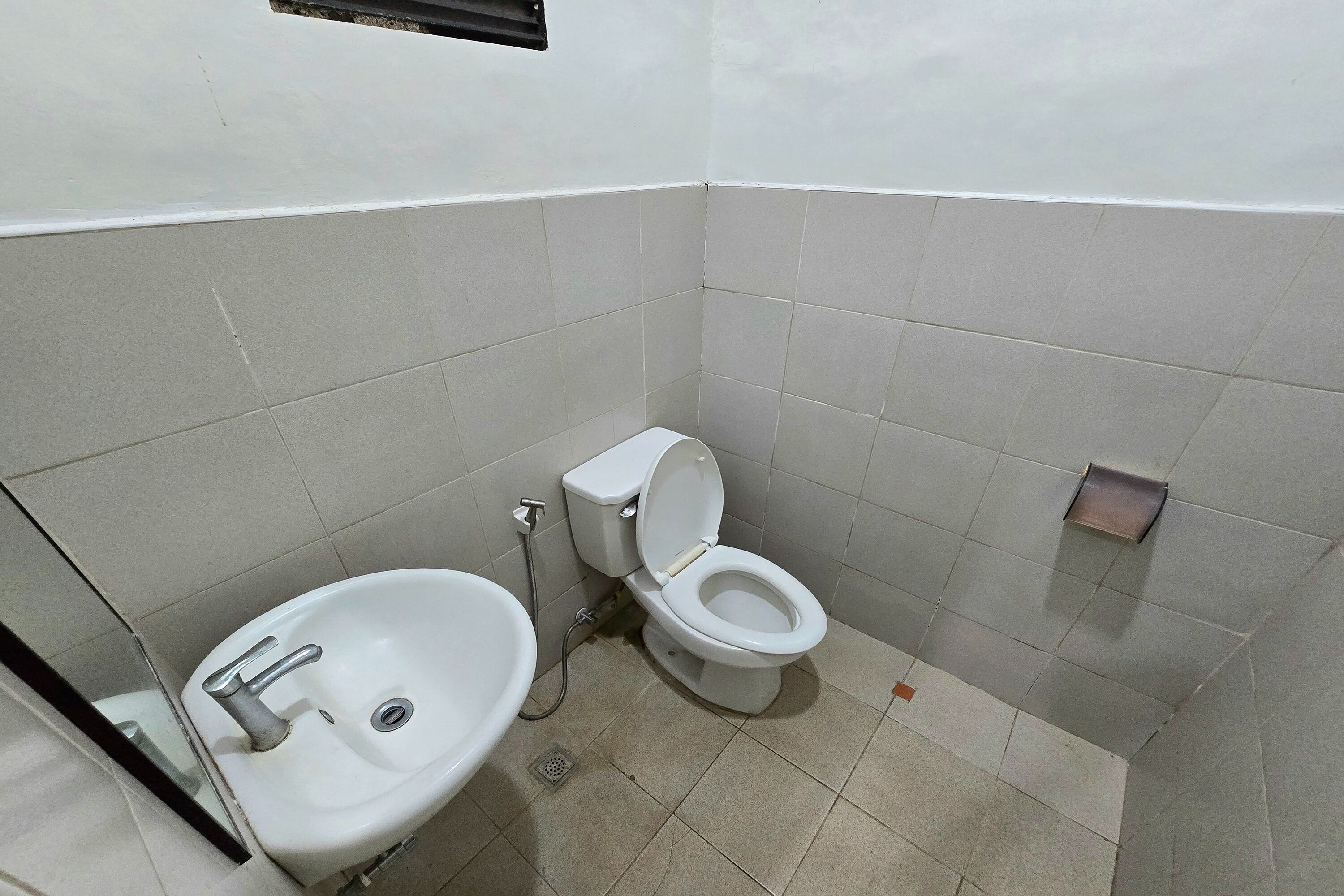 Une petite salle de bain avec un lavabo blanc, des toilettes et une douche.