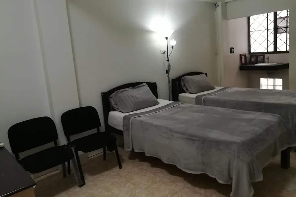 Una habitación con dos camas, un escritorio y sillas.