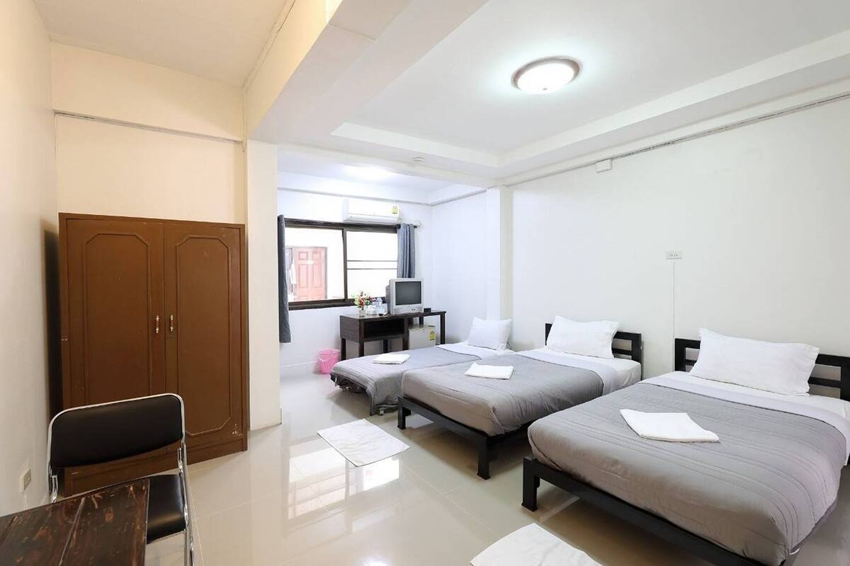 Habitación de hotel con dos camas, un escritorio, un televisor y un armario.