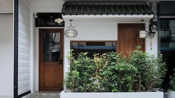 A traditional Japanese entrance with a wooden door, tiled roof, and hanging lanterns.