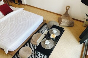 Une chambre à coucher bien rangée, avec un lit, un plateau noir orné d’objets décoratifs et un panier en osier.