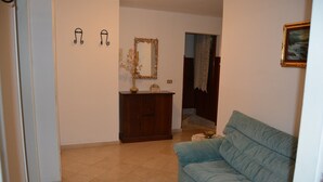 A living room with a blue sofa, a wooden cabinet, and a mirror with a decorative frame. - Flat with garden closed to see (Ripa- Pozzi-Ponterosso)