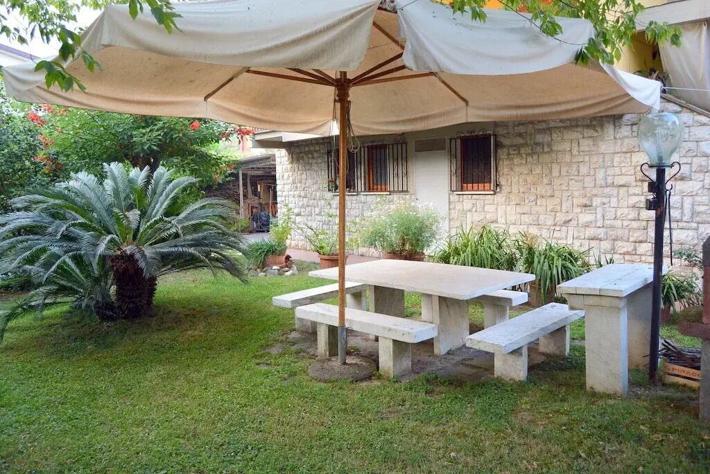 A stone house with a patio area featuring a picnic table and a large umbrella.
