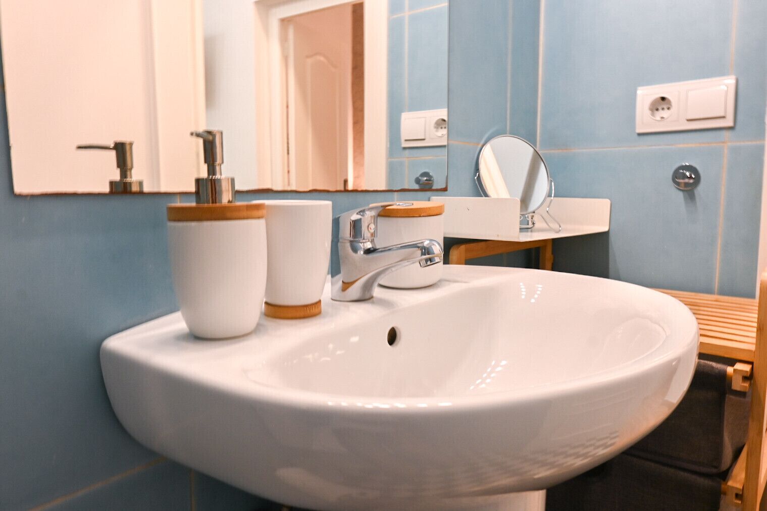Une salle de bain avec un lavabo blanc, un miroir et un meuble-lavabo en bois.