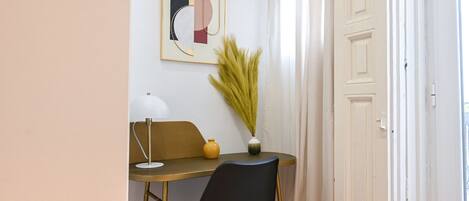 Une pièce comprenant un bureau, une chaise, une lampe, un vase et un tableau accroché au mur.