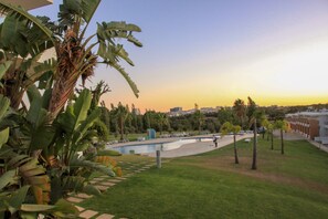 A landscaped area with a pool, palm trees, and a view of a cityscape at sunset. - Sul House - 2 bedroom house
Rest and tranquility in the heart of Albufeira! (Albufeira)