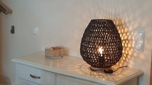 Ein weißer Schreibtisch mit einer dekorativen Lampe, einem gerahmten Zitat an der Wand und einer kleinen Schale auf dem Schreibtisch.
