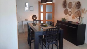 Ein Essbereich mit einem langen Tisch, Stühlen, einem schwarzen Schrank und Wanddekoration.