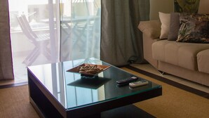 Ein Wohnzimmer mit Glastisch, einer Couch und Blick ins Freie.