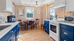Eine moderne Küche mit Holzwänden, einem Essbereich mit Tisch und Stühlen sowie einem großen Herd.