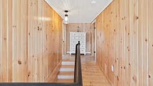 Ein holzgetäfelter Flur mit einer weißen Kommode und einer Treppe.
