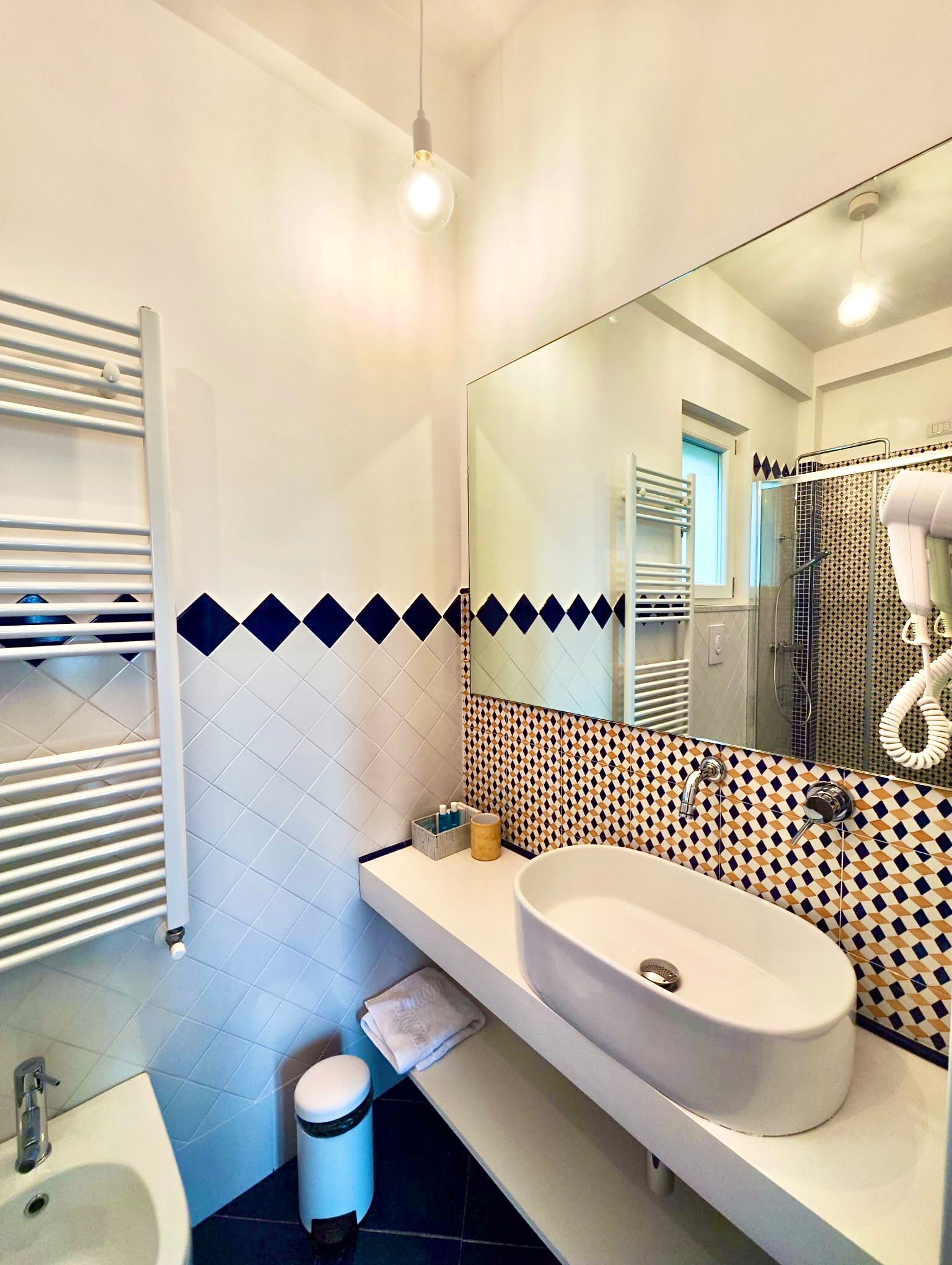 A modern bathroom with a white sink, a mirror, and patterned tiles.