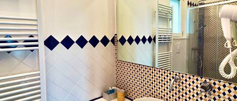 A modern bathroom with a white sink, a mirror, and patterned tiles.