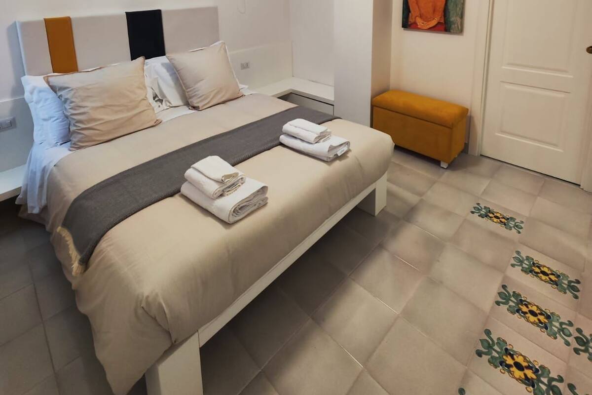 A modern bedroom with a bed, bedside table, and a painting on the wall.