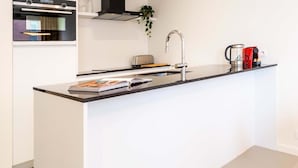 A modern kitchen with a central island, built-in oven, and stainless steel appliances.