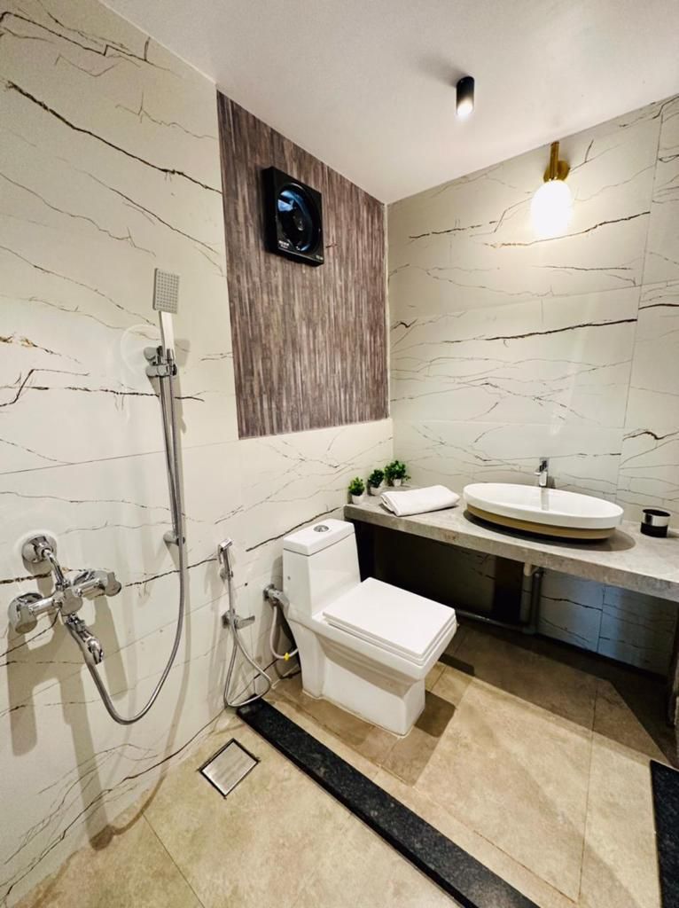 Et moderne badeværelse med en marmorvæg, toilet, vask og brusebad.