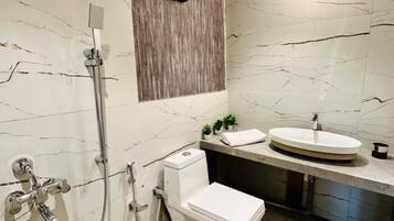 Et moderne badeværelse med en marmorvæg, toilet, vask og brusebad.