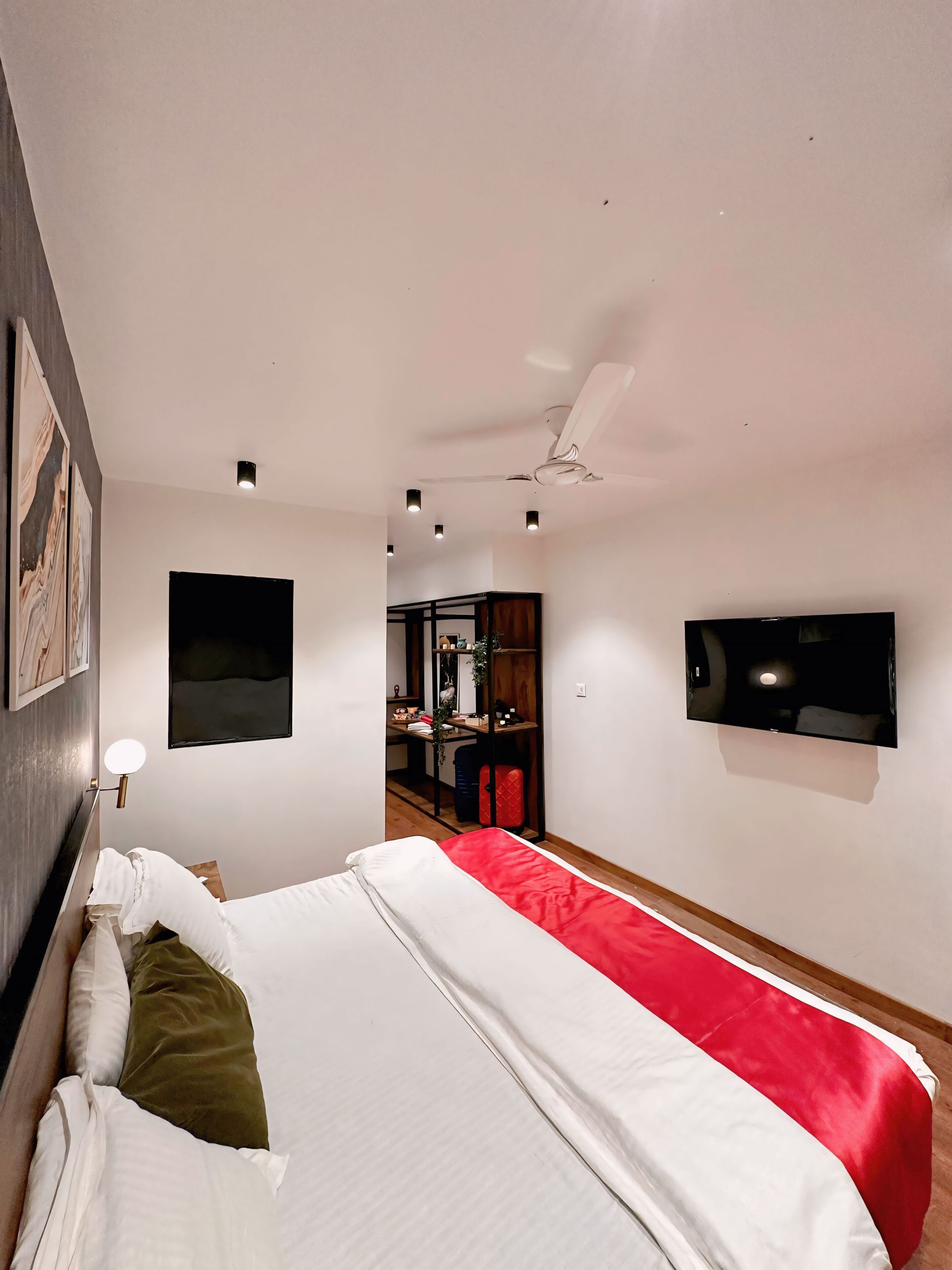 Une chambre d’hôtel moderne équipée d’un grand lit, d’un bureau, d’une télévision et d’un ventilateur de plafond.