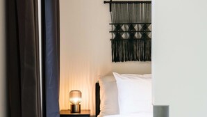 A bedroom with a bed, a bedside table with a lamp, and a macrame wall hanging. - Wonderful 1BR apartment in Antwerp (Antwerpen)
