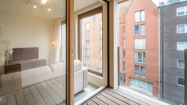 Un apartamento moderno con balcón, amplias ventanas y vistas a edificios vecinos.