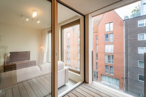 Un appartamento moderno con un balcone, ampie finestre e vista sugli edifici circostanti.