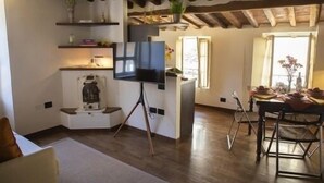 Un salon confortable avec un téléviseur, une machine à café et un coin repas avec une table mise pour deux personnes.