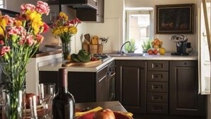 Une cuisine avec des meubles de couleur sombre, un îlot central et une fenêtre.