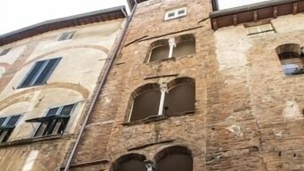 Un immeuble à plusieurs étages, doté de fenêtres en arc de cercle et d’une entrée centrale surmontée d’un portail en métal.