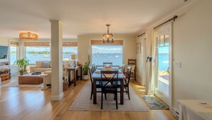 Un amplio salón con mesa de comedor, sofás y vista al mar.