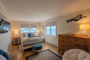 A bedroom with a bed, bedside tables, a dresser, a chair, and a window with blinds.