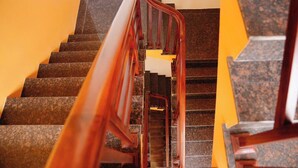 Una escalera con barandilla de madera y peldaños de granito.