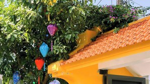 Un edificio amarillo con techo de tejas y un árbol adornado con ornamentos de colores.