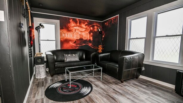 Un salon moderne avec un canapé en cuir noir, une table basse en verre et un disque vinyle posé sur le sol.