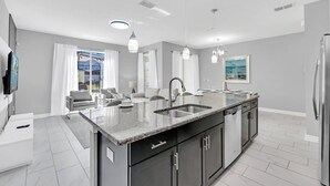 A modern kitchen with a large island, stainless steel appliances, and a dining area with a view. - Marvel | Mickey | Splash Pool | 4 Miles Disney 4876 (Kissimmee)
