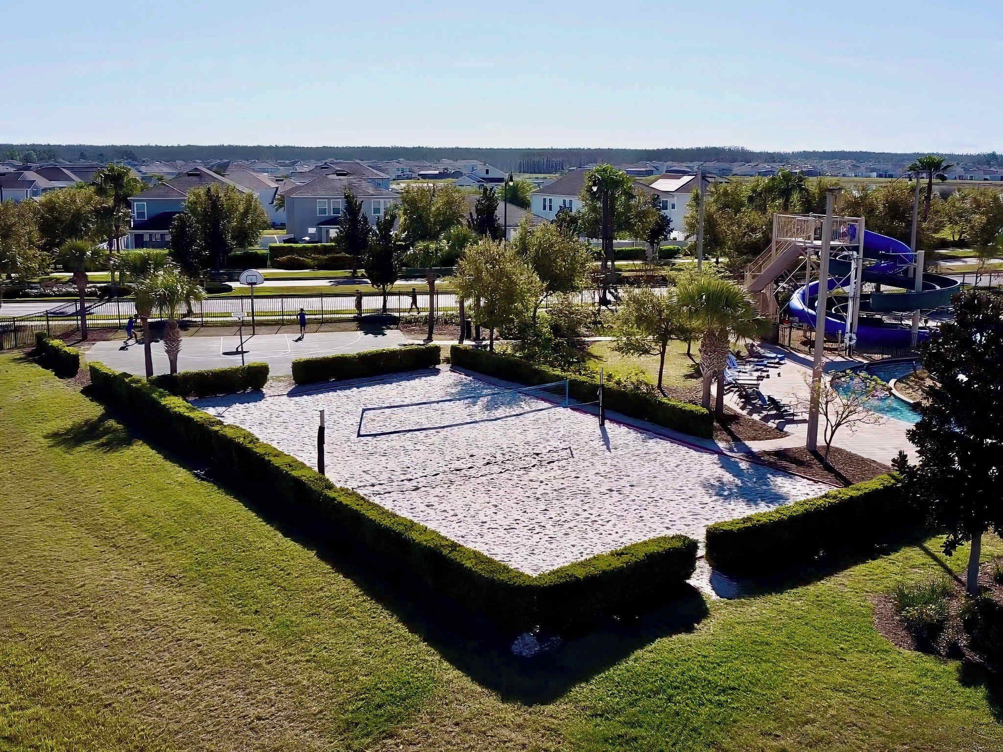 A park with a sandy play area, a water slide, and a pool.