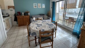 A compact kitchen with a dining area, a sofa, and a large window with a view.