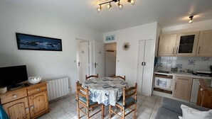 A compact living space with a dining table, chairs, a TV, a kitchen area, and a sofa.