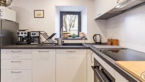 A modern kitchen with a built-in oven, a coffee machine, and a kettle. - Charming cottage on hillside - Private garden, parking (Canville-la-Rocque)
