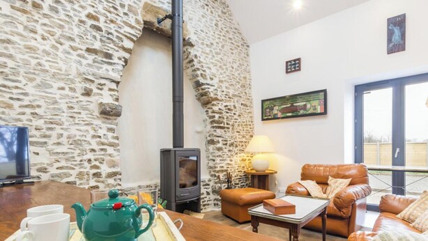 A stone wall, a fireplace, a sofa, a table with a tray, and a painting. - Charming cottage on hillside - Private garden, parking (Canville-la-Rocque)